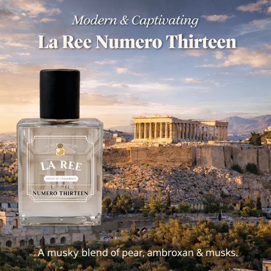 A bottle of La Ree Numero Thirteen perfume is shown in front of a scenic background of the Parthenon in Athens at sunset. The text reads 'Modern & Captivating La Ree Numero Thirteen' and 'A musky blend of pear, ambroxan & musks.